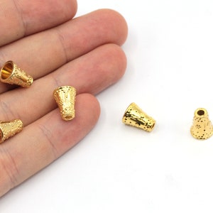 May include: Five gold-coloured metal cone-shaped end caps with a textured surface.