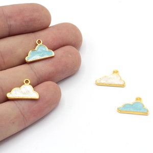 May include: Three gold-coloured cloud charms with a white or light blue enamel finish. The charms have a loop at the top for attaching to jewellery or other crafts.