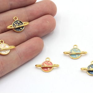 May include: Five gold-tone charms shaped like planets with a ring around them. Each planet has a different colored enamel finish: black, white, light blue, coral, and dark blue. Each planet has a crescent moon and stars on the surface.