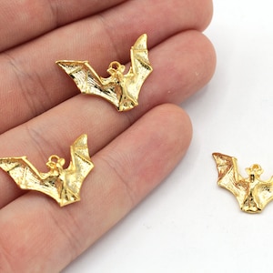 Peut inclure: Trois breloques en m&eacute;tal de couleur dor&eacute;e en forme de chauve-souris. Les chauves-souris sont en position de vol, les ailes d&eacute;ploy&eacute;es.