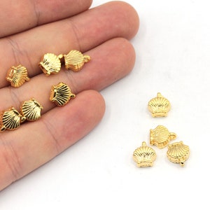 May include: A collection of ten gold-colored metal seashell charms. The charms are small and detailed, with a realistic seashell design.