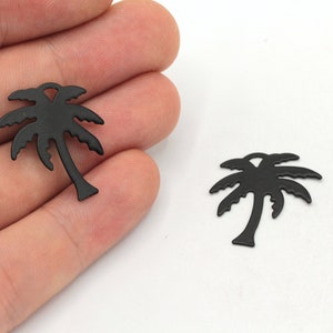 May include: Two black metal palm tree charms. The charms are about 2 inches tall and have a detailed design.