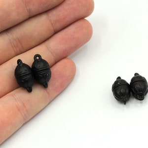 May include: Two black magnetic clasps for jewelry making. The clasps are oval shaped and have a decorative design.