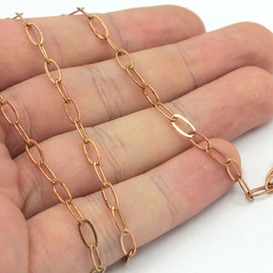 May include: A gold chain with oval links. The chain is lying on a hand.