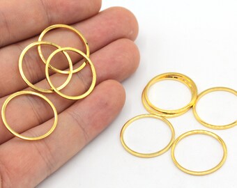 May include: A set of gold-colored metal jump rings. The rings are different sizes and are arranged in a pile on a hand.