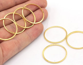 May include: Five gold-colored metal rings, each with a smooth, rounded edge. The rings are stacked on top of each other, with two more rings lying flat on a white surface.