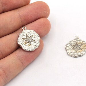 May include: Two silver-toned metal charms with a hammered texture. Each charm features a five-pointed star with clear rhinestones.