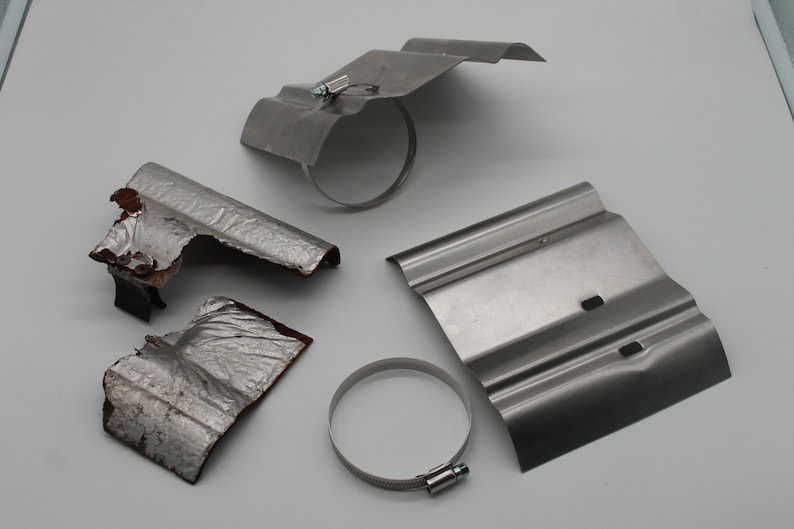 Puede incluir: Cuatro escudos t&eacute;rmicos de metal para un sistema de escape. Dos est&aacute;n intactos, uno est&aacute; parcialmente da&ntilde;ado y uno est&aacute; en pedazos. Los escudos son plateados y tienen una superficie corrugada. Hay dos abrazaderas de metal plateadas.