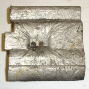 Puede incluir: Primer plano de un objeto de metal plateado con una superficie texturizada. El objeto tiene dos peque&ntilde;os agujeros con remaches met&aacute;licos.