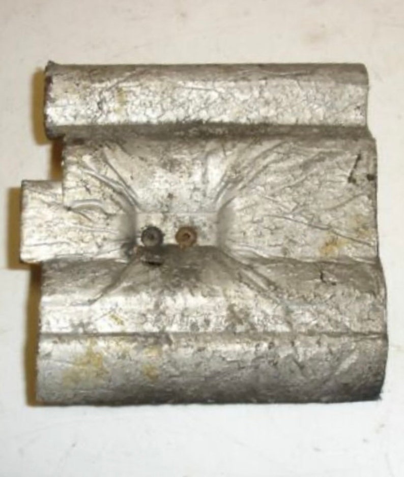 Puede incluir: Primer plano de un objeto de metal plateado con una superficie texturizada. El objeto tiene dos peque&ntilde;os agujeros con remaches met&aacute;licos.