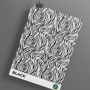 May include: A black and white zebra print design on a rectangular poster. The word "BLACK" is printed in bold white letters at the bottom. The poster is hanging from a metal clip against a gray background.
