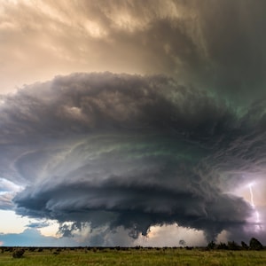 Puede incluir: Una gran nube de tormenta oscura y amenazante con una nube en forma de embudo que se forma debajo. Un rayo cae de la nube.