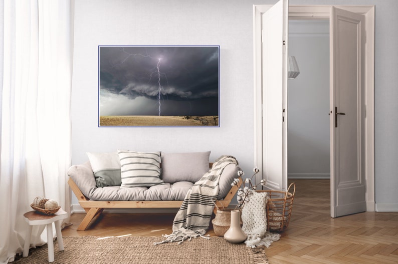 May include: A photograph of a lightning strike in a dark, stormy sky over a field of dry grass. The lightning bolt is white and bright, and the sky is dark and dramatic.