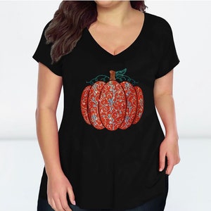 May include: Black v-neck t-shirt with a sparkly orange pumpkin design. The pumpkin has a green stem and leaves.