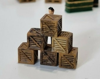 May include: A stack of six wooden crates, some with a brown stain, others with a natural wood finish. The crates are arranged in a pyramid shape, with a small figurine standing on top.