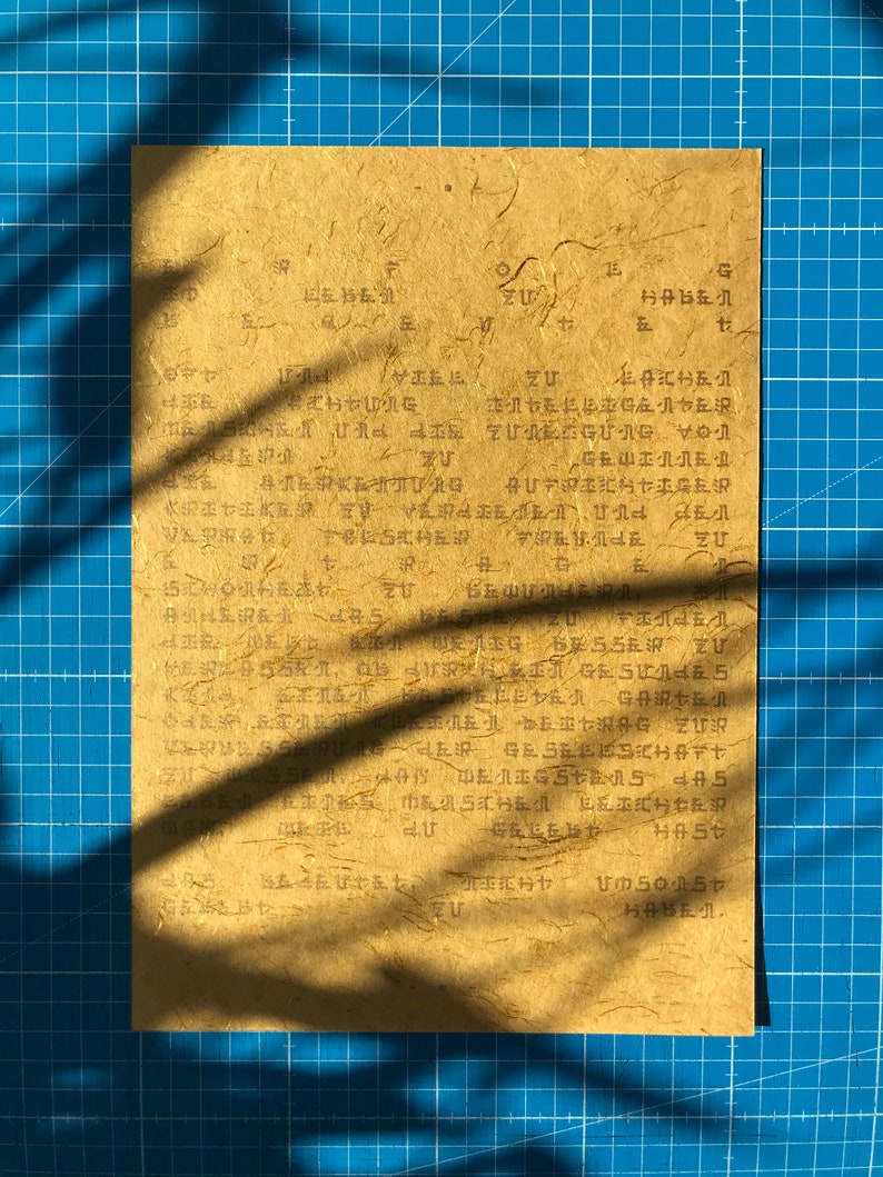 May include: A close-up of a piece of paper with handwritten text in Japanese. The paper is light brown and has a textured surface. The text is in black ink and is difficult to read.