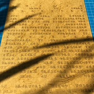 May include: A close-up of a piece of paper with Japanese text written on it. The paper is a light brown colour and has a rough texture. The text is written in black ink and is difficult to read.