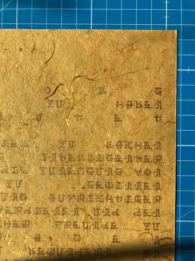 May include: A close-up of a piece of paper with handwritten text in black ink. The paper is textured and has a light brown colour. The text is in a cursive style and is difficult to read. The text includes the words "zu" and "g".