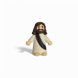 May include: A small, figurine of a religious figure, depicted with brown hair and beard, wearing a white robe and a black sash. The figure has a smiling expression and is standing upright. The figurine is made of a light-colored material.