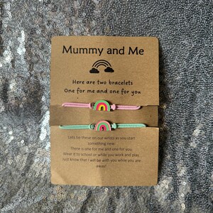 May include: A card with the text "Mummy and Me" and a rainbow graphic. The card says "Here are two bracelets, one for me and one for you."  The card also includes a message about tying the bracelets on wrists and wearing them to school or work.