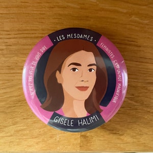 Peut inclure: Un bouton rond avec un portrait de Gisele Halimi, une femme aux cheveux bruns et un haut rose. Le bouton a une bordure rose et bleu foncé avec du texte français, dont "LES MESDAMES" et "Gisele Halimi."