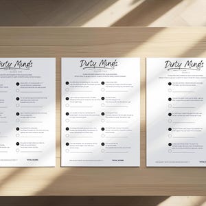 May include: Three white sheets of paper with the title "Dirty Minds" printed in a cursive font. Each sheet contains a series of questions with corresponding circles for answers. The sheets are arranged on a wooden surface.