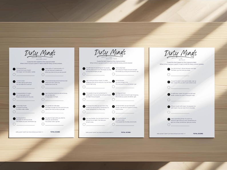 May include: Three white sheets of paper with the title "Dirty Minds" printed in a cursive font. Each sheet contains a series of questions with corresponding circles for answers. The sheets are arranged on a wooden surface.