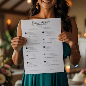 May include: A person holds a white sheet of paper with the title "Dirty Minds" and a list of fill-in-the-blank questions. The paper has a total score of 3 at the bottom. The person is wearing a teal dress.
