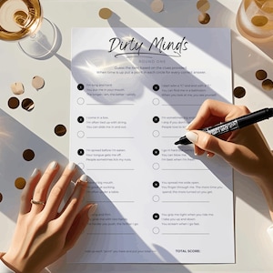 May include: A game of "Dirty Minds" is displayed on a white sheet of paper. The game sheet is on a white table, with a person's hand holding a black marker, ready to fill in the answers. Gold confetti and glasses of champagne are also on the table.