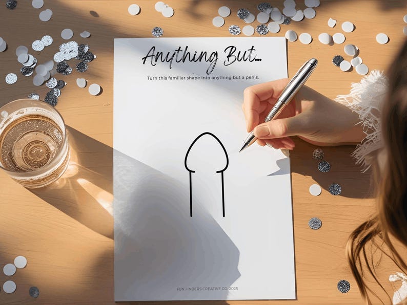 May include: A white sheet of paper with the text "Anything But..." and a simple line drawing of a penis. A person is holding a pen, ready to draw. Confetti and a glass of liquid are on the wooden table.