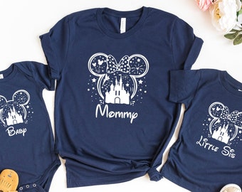 May include: Three navy blue t-shirts with a white silhouette of Mickey Mouse ears with a castle inside. The shirts say "Mommy", "Baby", and "Little Sis".