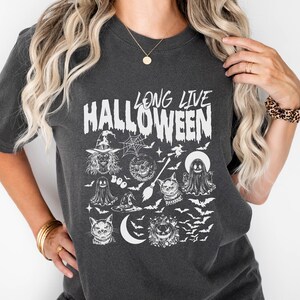 May include: A dark grey t-shirt with a white graphic print that says "Long Live Halloween". The graphic includes a witch, a ghost, a cat, a pumpkin, and bats.