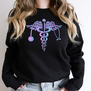 May include: Black sweatshirt with a pink and blue medical caduceus symbol on the front.