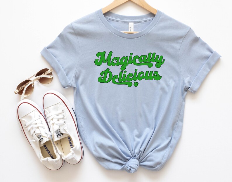 May include: A light blue t-shirt with the text "Magically Delicious" in green with shamrock symbols.