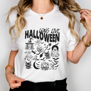May include: White t-shirt with a black graphic print that says "Long Live Halloween" and features a witch, ghosts, bats, a cat, a crescent moon, and a pumpkin.