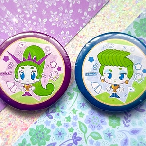 May include: Two round buttons with cartoon characters. One button is purple with a green-haired character and the word "velvet!". The other button is blue with a green-haired character and the word "veneer". Both have star and diamond accents.