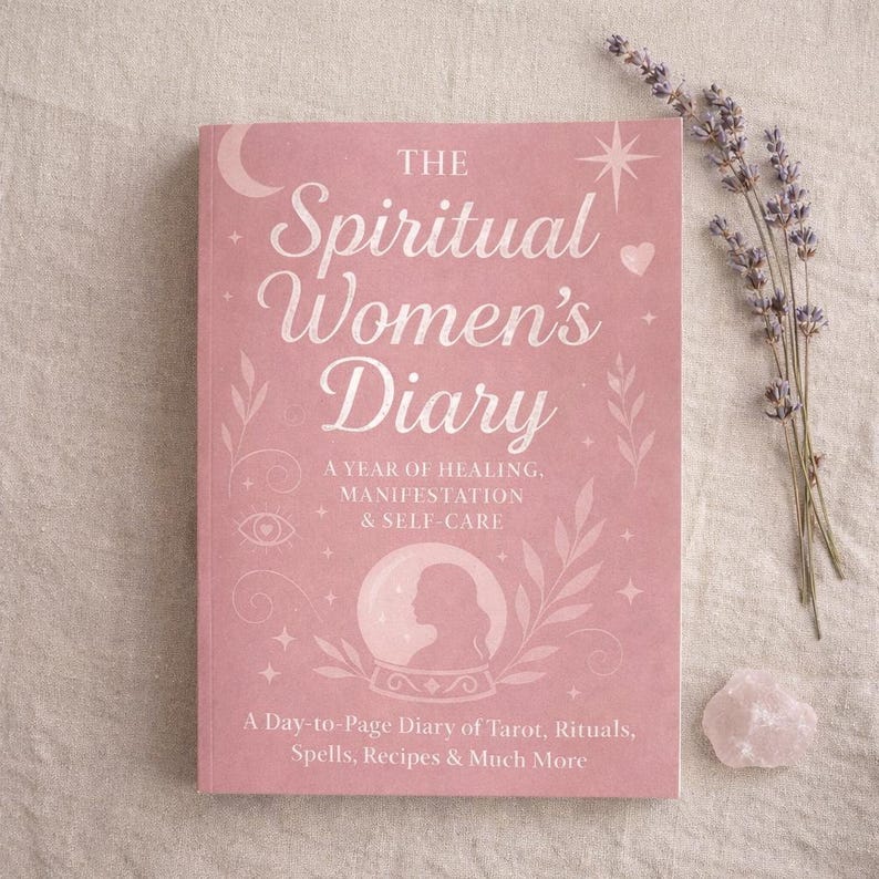 K&ouml;nnte beinhalten: Ein rosa Tagebuch mit dem Titel "The Spiritual Women's Diary" in wei&szlig;er Schrift und dekorativen Illustrationen. Das Buch enth&auml;lt Texte &uuml;ber Heilung, Manifestation und Selbstf&uuml;rsorge. Ein Lavendelzweig und ein Rosenquarz-Kristall liegen daneben.