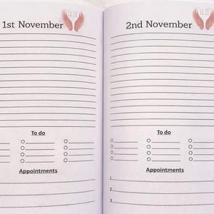 K&ouml;nnte beinhalten: Offene Notizbuchseiten mit linierten Abschnitten f&uuml;r Notizen, To-Do-Listen und Termine. Die Daten "1. November" und "2. November" stehen oben, mit Engelsfl&uuml;gel-Illustrationen. Die Seiten sind wei&szlig; mit schwarzem Text.