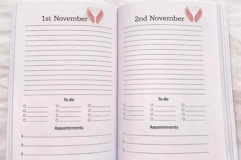 K&ouml;nnte beinhalten: Offene Notizbuchseiten mit linierten Abschnitten f&uuml;r Notizen, To-Do-Listen und Termine. Die Daten "1. November" und "2. November" stehen oben, mit Engelsfl&uuml;gel-Illustrationen. Die Seiten sind wei&szlig; mit schwarzem Text.