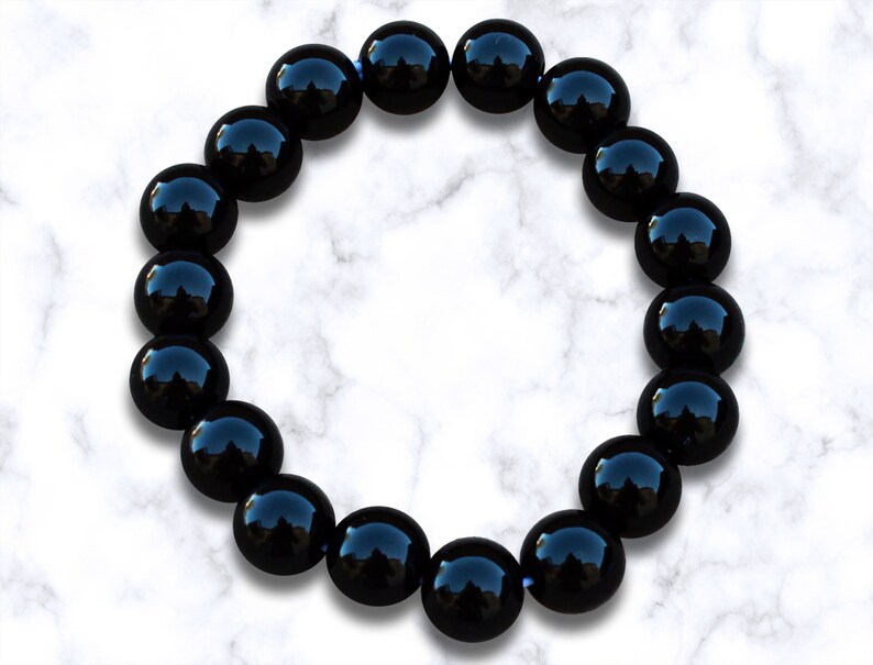 May include: A black beaded bracelet with shiny, round beads. The bracelet is made of natural black onyx stones.