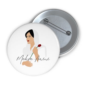 Peut inclure: Un bouton blanc avec une illustration en noir et blanc d'une femme portant un foulard blanc et tenant une rose rouge. Le texte "Mahsa Amini" est écrit en cursive noire sous l'illustration.