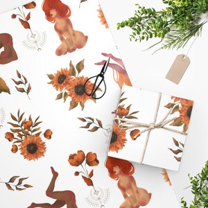 May include: White wrapping paper with a repeating pattern of sunflowers, leaves, and figures. The figures are nude and have red hair. The sunflowers are yellow with orange centers. The leaves are green.