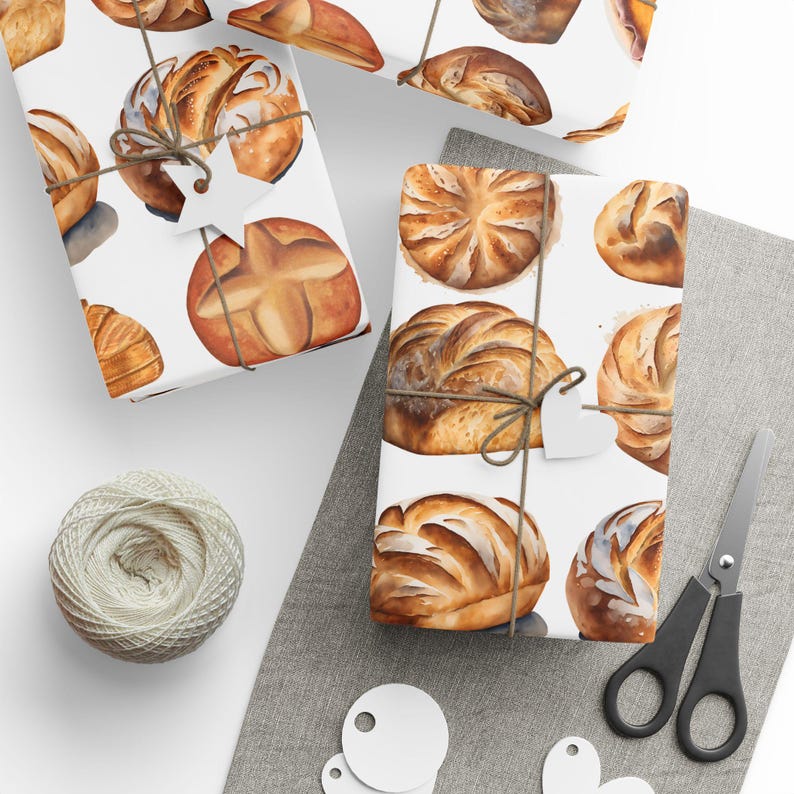 K&ouml;nnte beinhalten: Ein Set aus drei wei&szlig;en Geschenkpapieren mit einem Aquarelldesign aus verschiedenen Broten und Br&ouml;tchen. Die Papiere sind mit Schnur und wei&szlig;en Papieretiketten verziert.