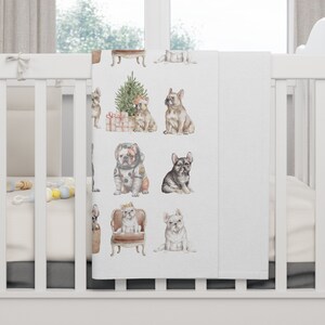 May include: White baby blanket with a repeating pattern of French Bulldogs in various poses. The dogs are wearing different outfits, including a space suit, a crown, and a Santa hat. The blanket is perfect for a nursery or a child's room.