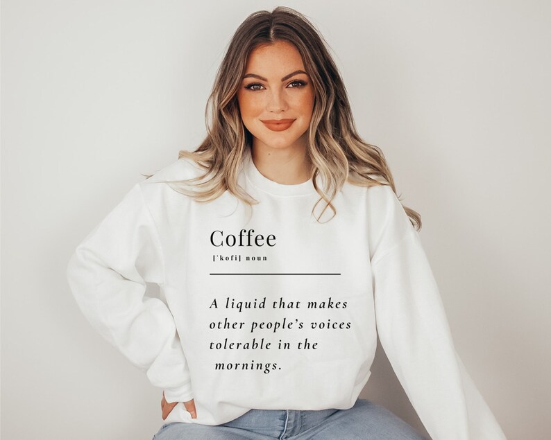 May include: White sweatshirt with the word "Coffee" and a definition: "A liquid that makes other people's voices tolerable in the mornings."