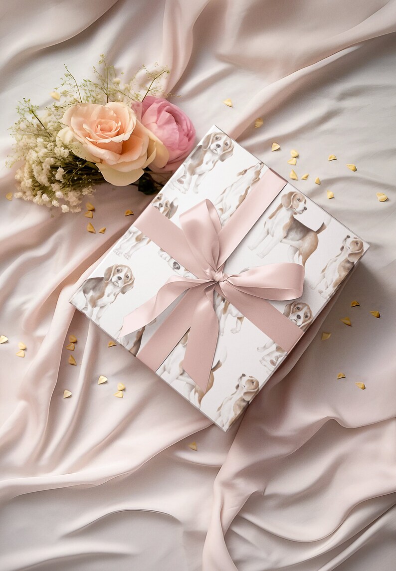 May include: A white gift box with a pink ribbon and a pattern of brown and white dogs. The box is on a pink fabric background with gold confetti.