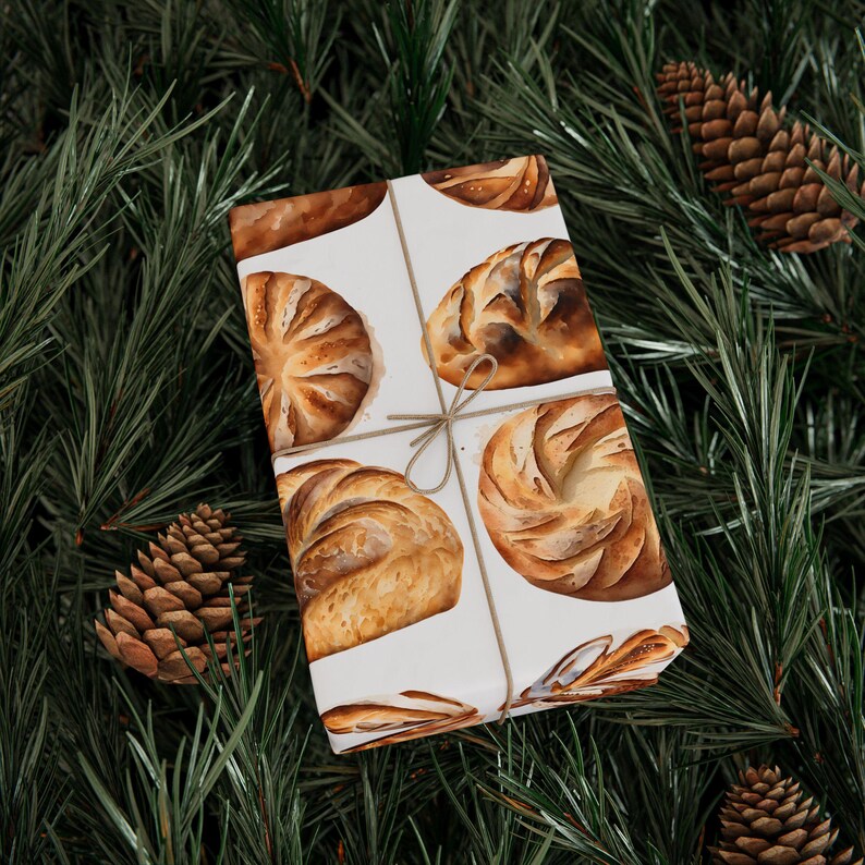 K&ouml;nnte beinhalten: Wei&szlig;es Geschenkpapier mit einer braunen Kordelschleife. Das Geschenkpapier zeigt ein sich wiederholendes Muster aus Aquarell-Illustrationen verschiedener Brotsorten.