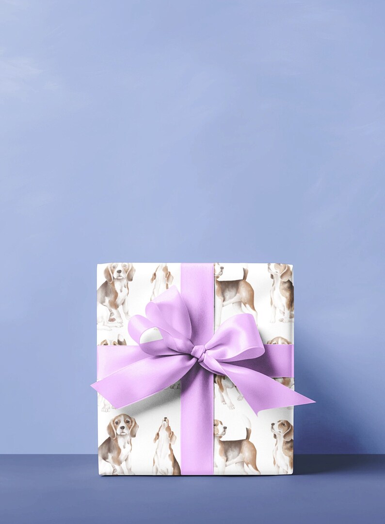 May include: A white gift box with a purple ribbon and a pattern of beagle dogs. The box is sitting on a light blue surface.