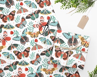 Puede incluir: Papel de regalo blanco con un patrón repetitivo de mariposas coloridas. Las mariposas son de varios tonos de rojo, naranja, amarillo, azul y verde. El papel es perfecto para envolver regalos o crear manualidades.