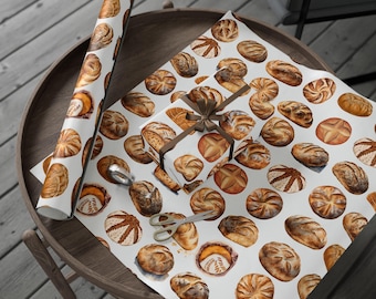 May include: White wrapping paper with a repeating pattern of watercolor illustrations of various types of bread. The paper is rolled up and a small gift box is wrapped with the paper.